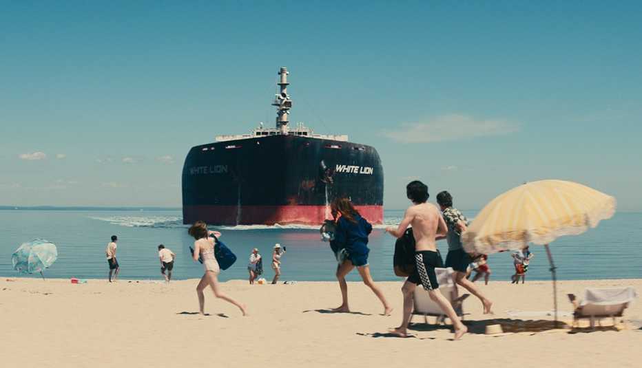 Farrah Mackenzie, Julia Roberts, Charlie Evans and Ethan Hawke running on the beach as an oil tanker approaches in the Netflix film "Leave the World Behind."