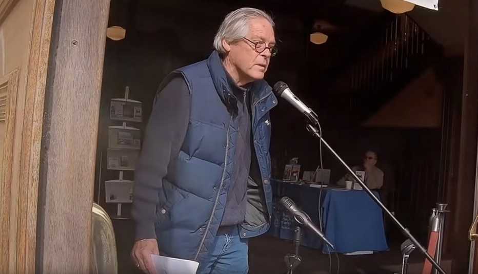 Journalist Greg O'Brien speaks into a microphone in the documentary Have You Heard About Greg