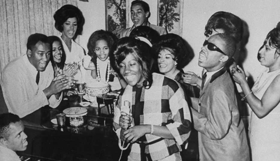 Berry Gordy and a group performing around a piano.