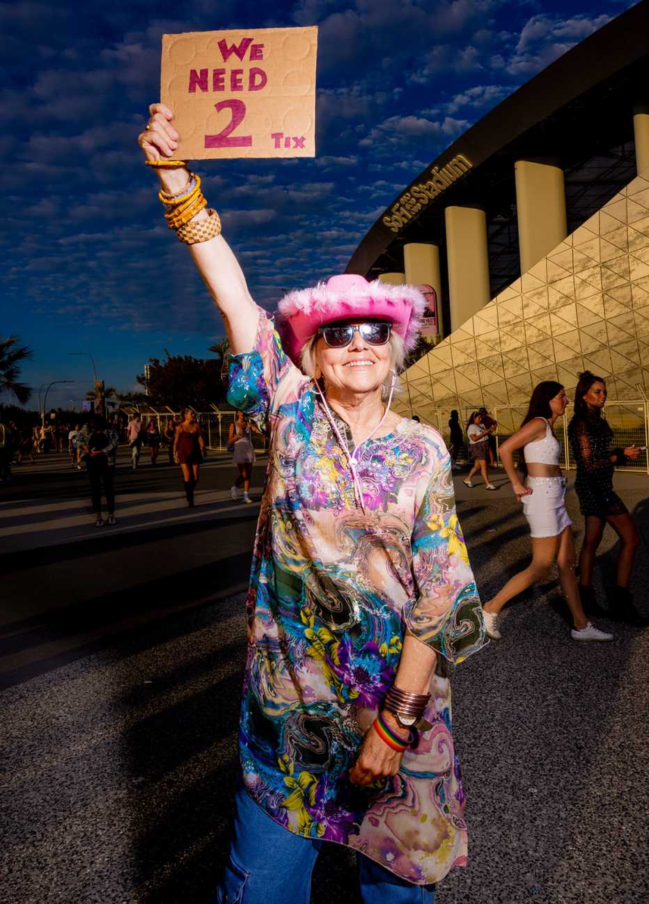 alison e edwards outside sofi stadium in los angeles california holding up a cardboard sign that says we need two tix