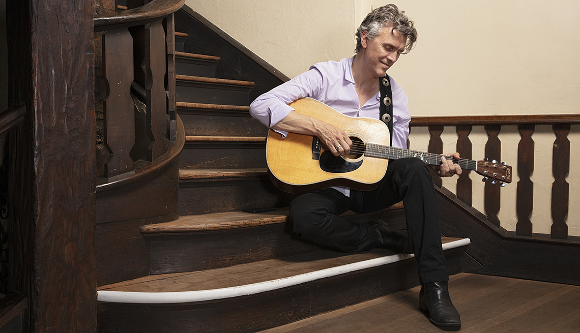 robert burke warren playing guitar sitting on a staircase