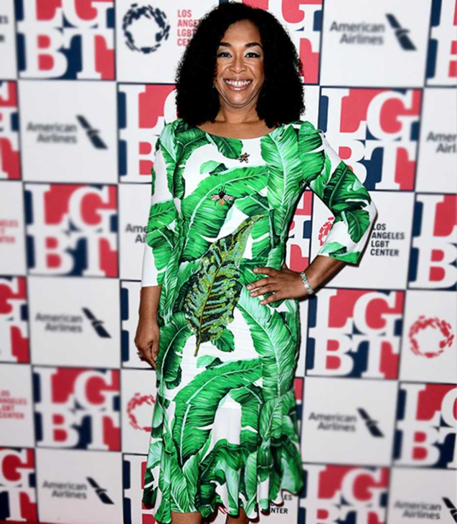 Shonda Rhimes in green-and-white leaf print dress with boatneck, 3/4 sleeves and ruffle hem.