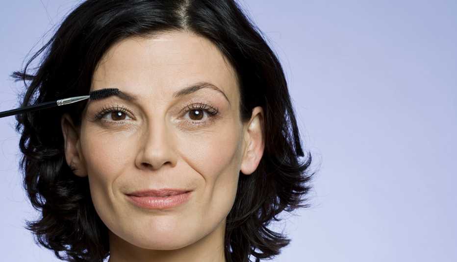 A woman using a makeup spoolie on her eyebrow