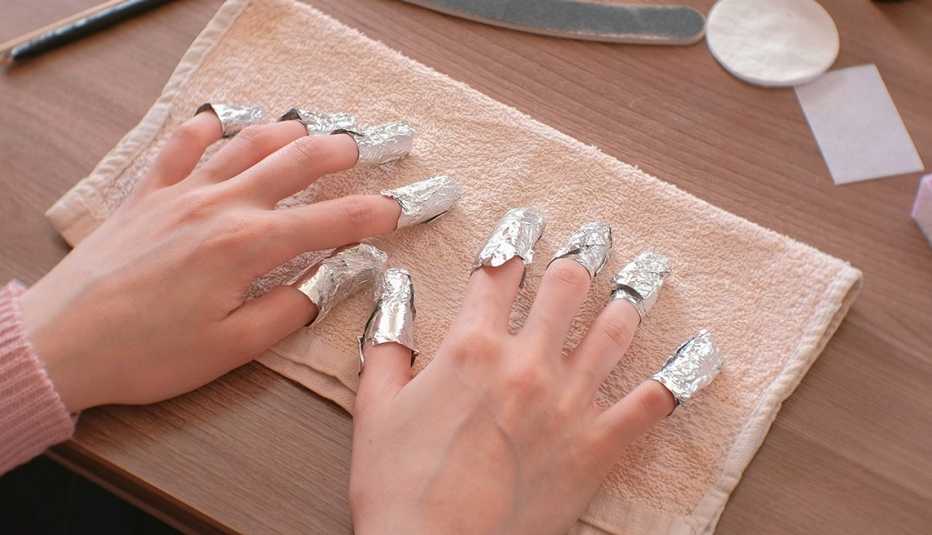 A woman removing gel polish using aluminum foil on each fingers