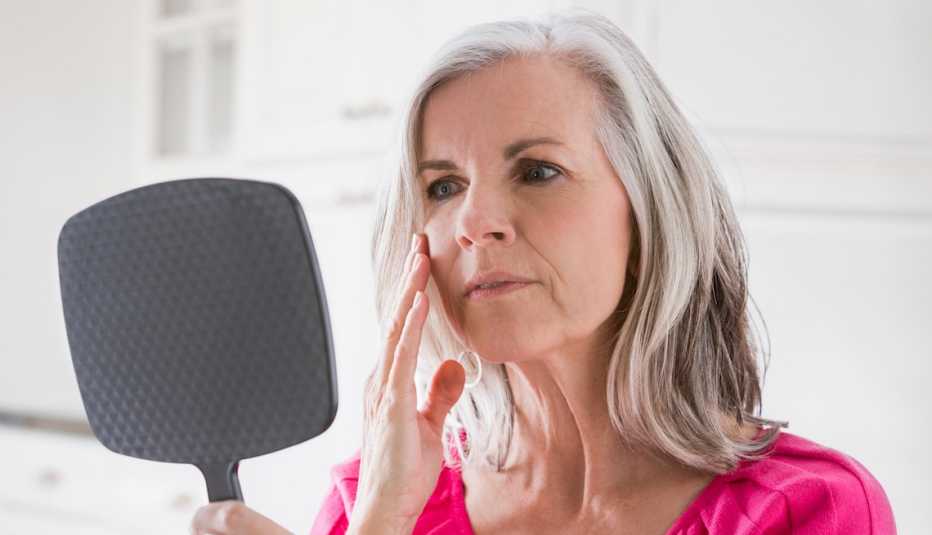 Caucasian woman looking at skin in mirror