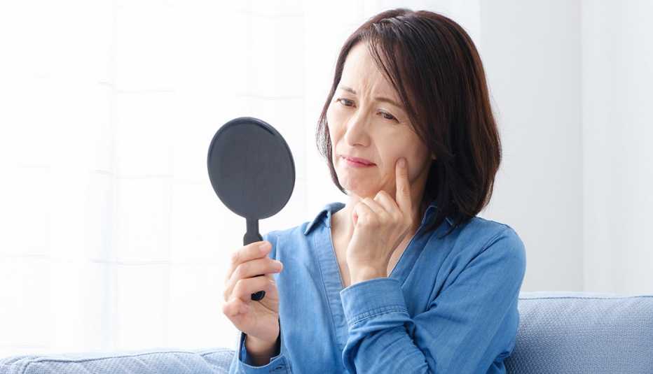 A woman holding and looking into a small mirror in her living room