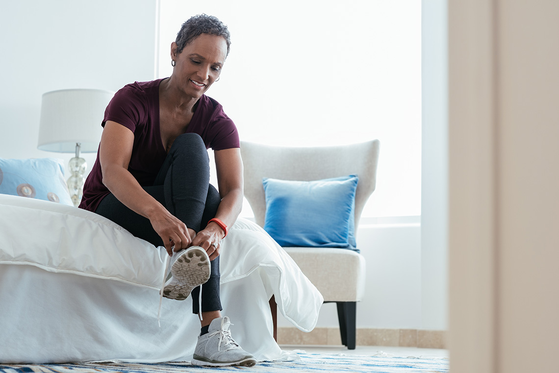 A woman putting on sneakers in bedroom