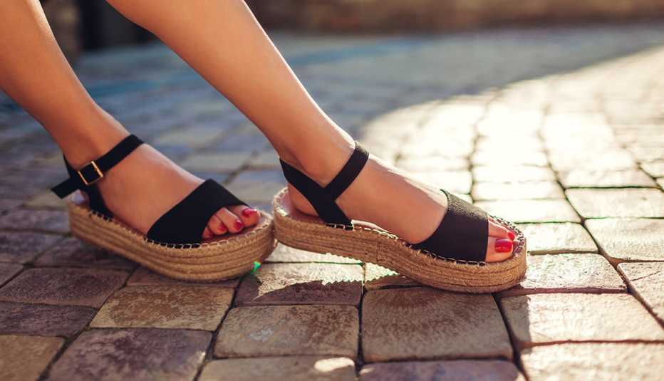 A closeup of a woman's feet wearing a pair of black sandals outdoors