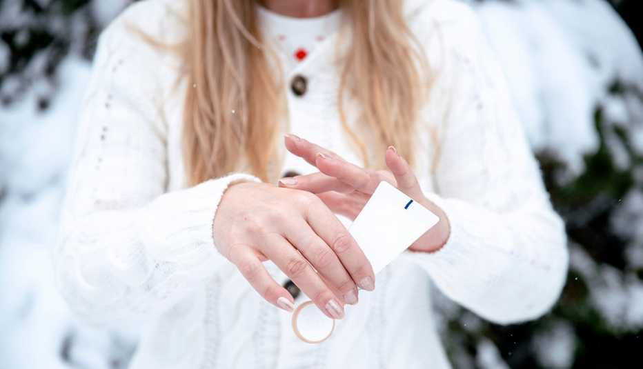A woman is applying hand cream outside in snowy weather