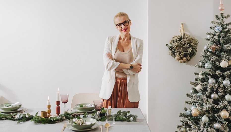 A woman standing with crossed arms in decorated dining room for a Christmas celebration