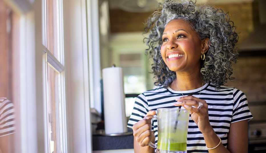 a woman with full curly hair drinking a smoothie
