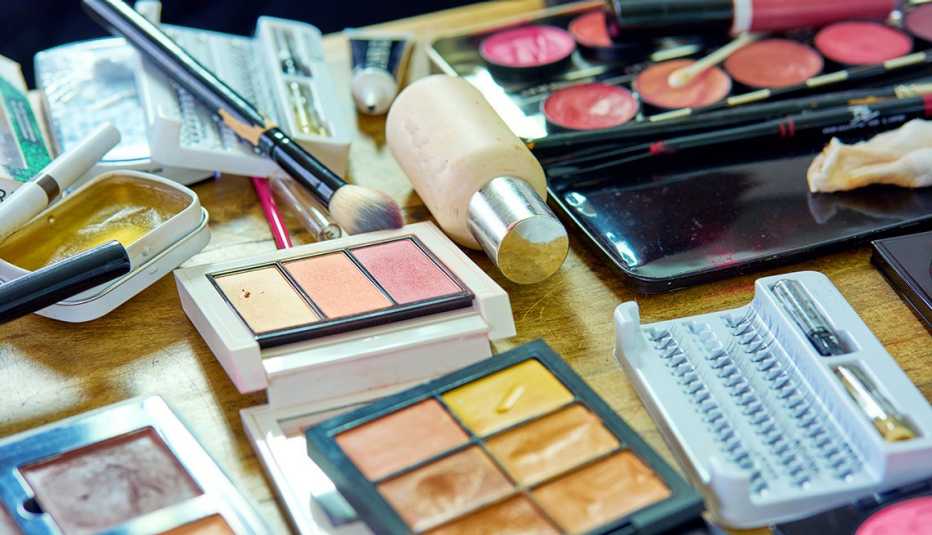 A messy table filled with old makeup products, brushes and tools