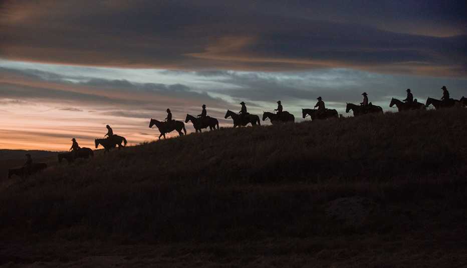 A group of people riding horses overlooking the sun in the horizon in the television series 1923 A group of people riding horses overlooking the sun in the horizon in the television series 1923