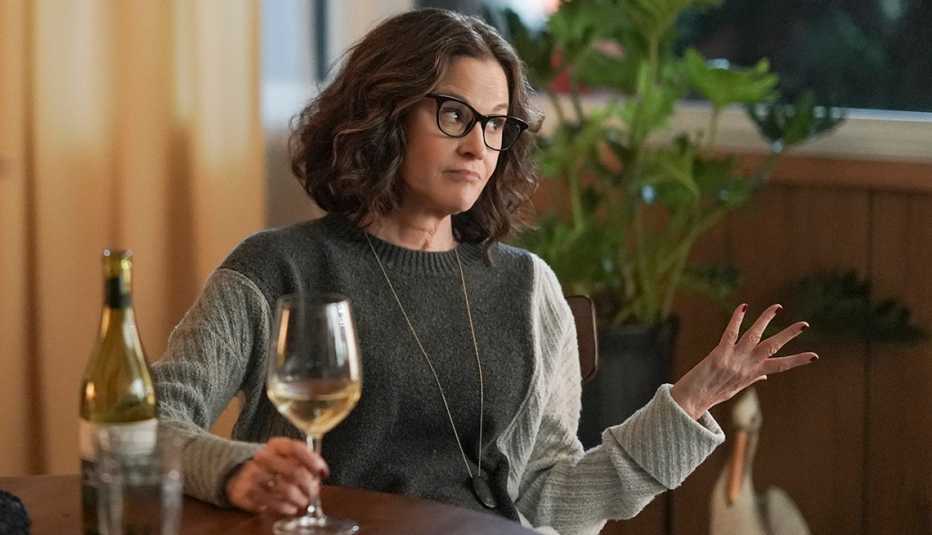Ally Sheedy holding a wine glass at a table on the TV series Single Drunk Female