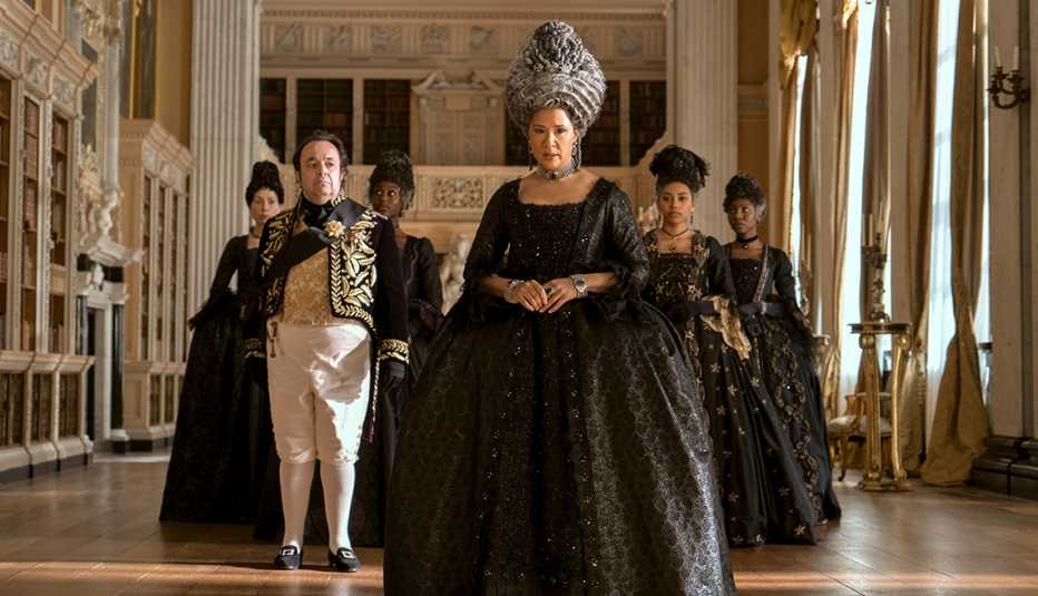 hugh sachs as brimsley and golda rosheuvel as queen charlotte with four other women standing behind them in still from queen charlotte  a bridgerton story