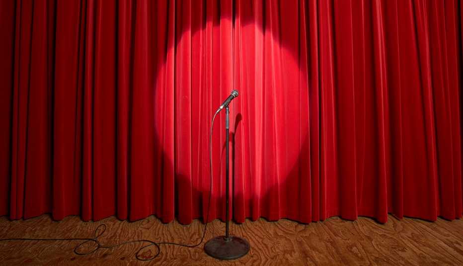 spotlight on microphone on stage in front of red curtain