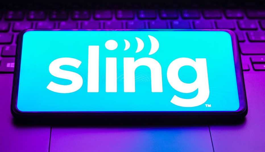 a sling tv logo is displayed on a smartphone screen that is laid on top of a computer keyboard