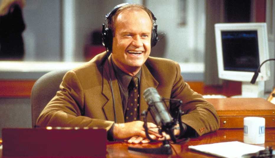 kelsey grammer as frasier crane wearing headphones and smiling during his radio show in the nbc series frasier
