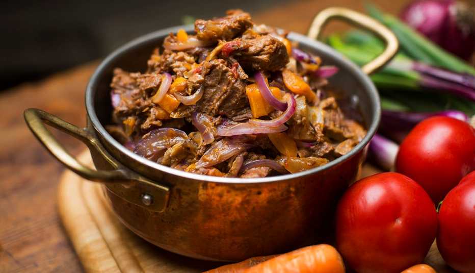 A pot full of meat placed on a tray next to vegetables in Chef's Table