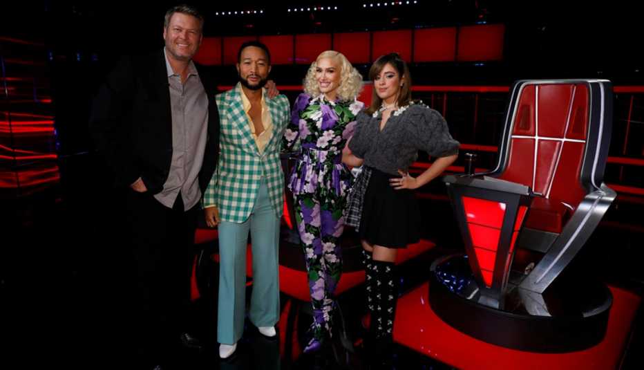 The Voice Season 22 coaches Blake Shelton, John Legend, Gwen Stefani and Camila Cabello pose for a photo together on stage next to a rotating chair