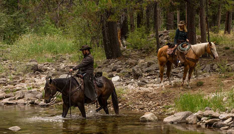 Cole Hauser and Kelly Reilly riding on horses outdoors in Yellowstone