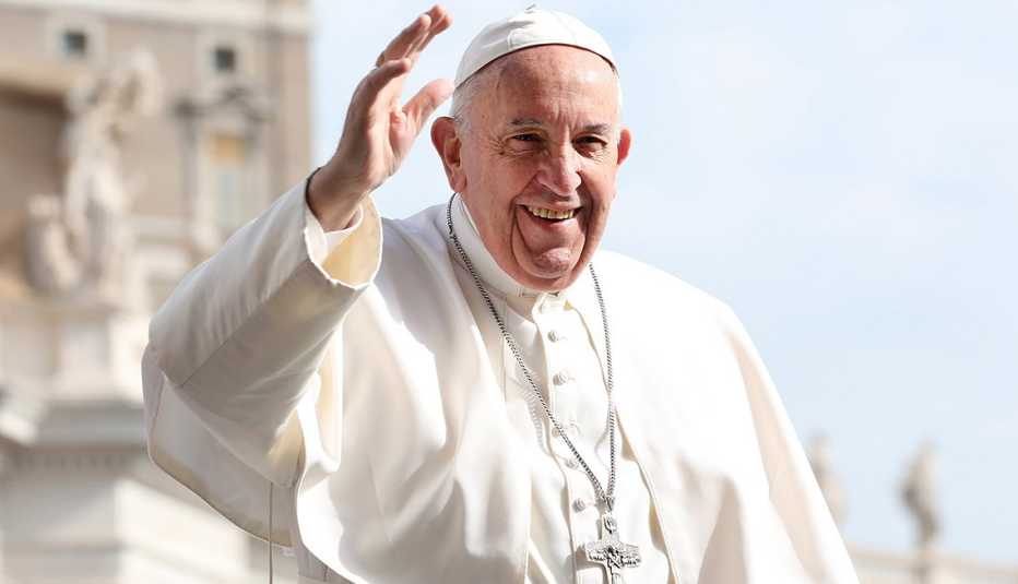 pope francis waves and smiles at a crowd