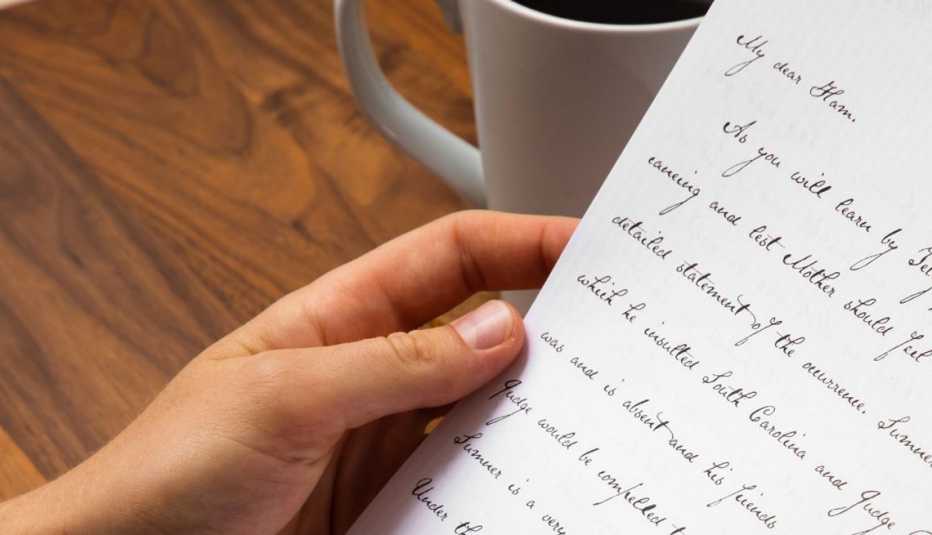 a hand holds a handwritten letter in neat script