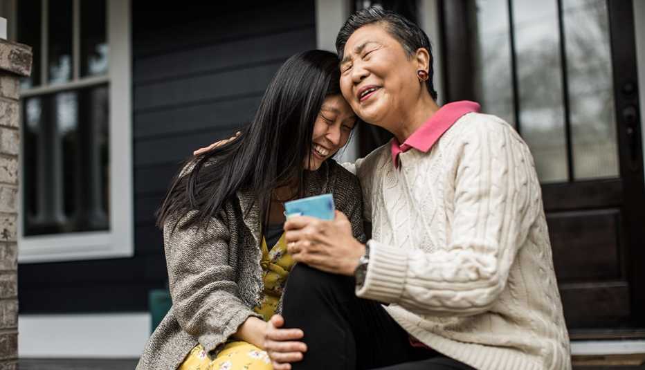 woman and her mother hugging and laughing on the porch