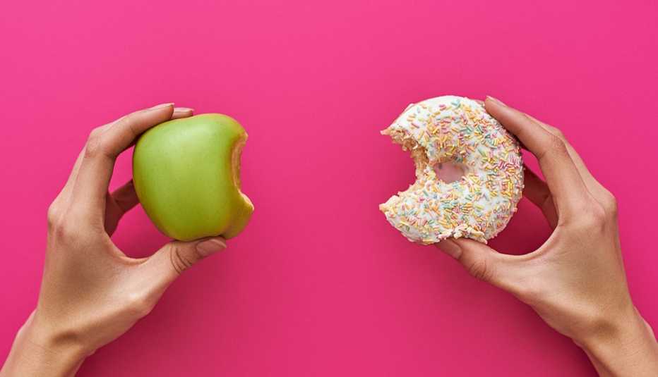 pair of hands, one holding an apple, one holding a donut