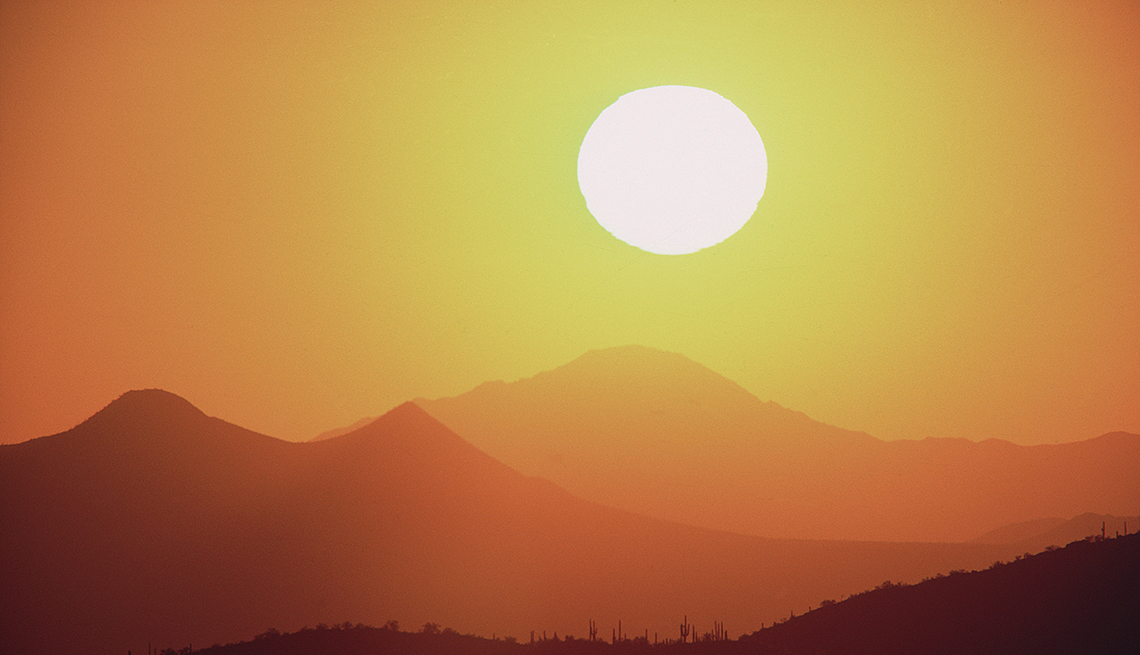 the sun in the sky above mountains