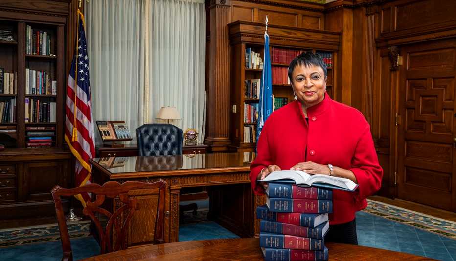 Librarian of Congress Carla Hayden stands in her office with a stack of books