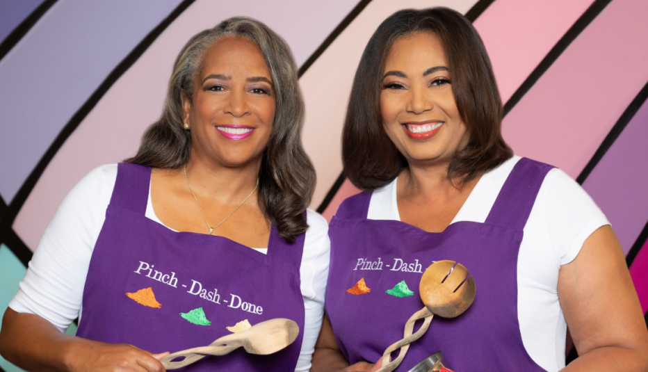 Beatrice Moore and Vernita Harris wearing aprons and holding cooking utensils.