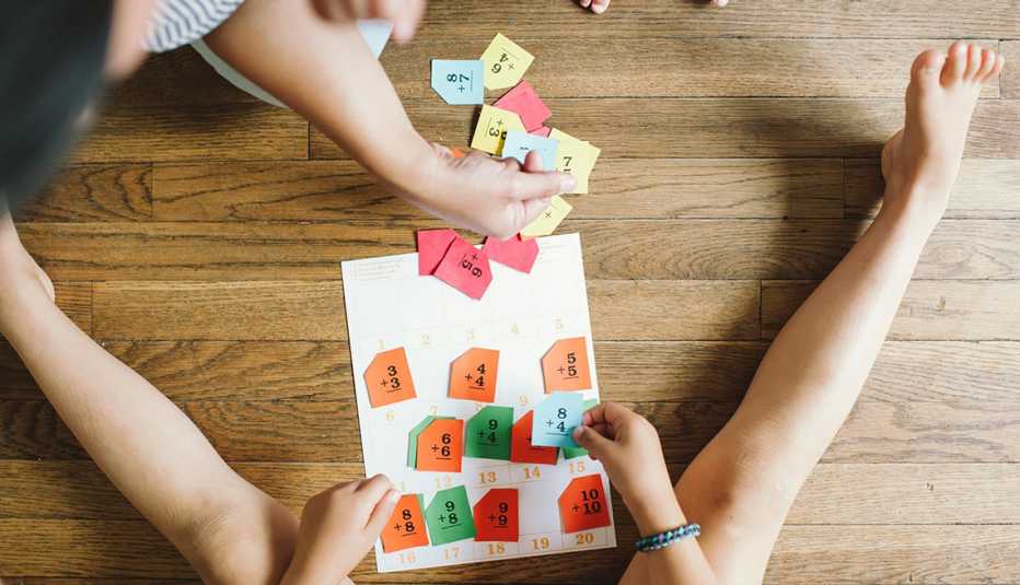 two kids sit on a hardwood floor while playing a learning game featuring colored tabs
