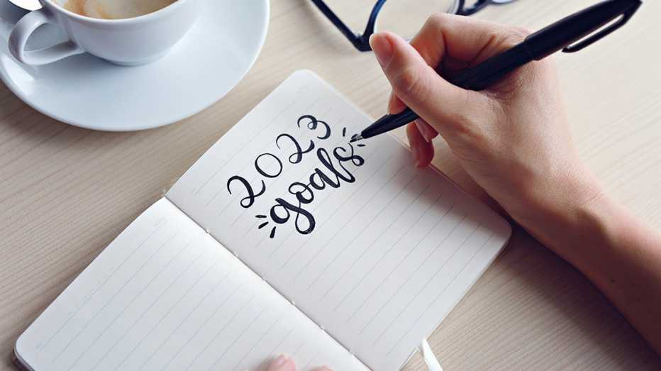 a person writings 2023 goals in a notepad