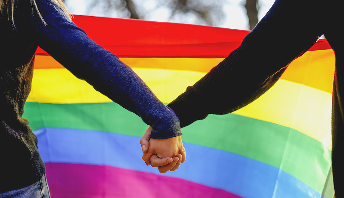 Two girls holding hands and a rainbow flag in support of the LGBT community
