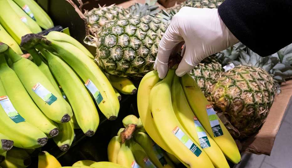 A woman with rubber gloves is shopping in an market.