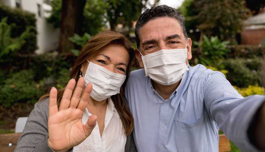 Couple posing for a photo together, wearing a mask, outdoors Couple posing for a photo together, wearing a mask, outdoors