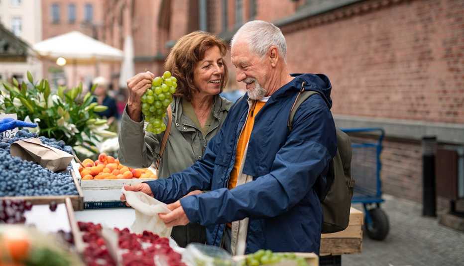A happy senior couple buying fruit outdoors on market in town.