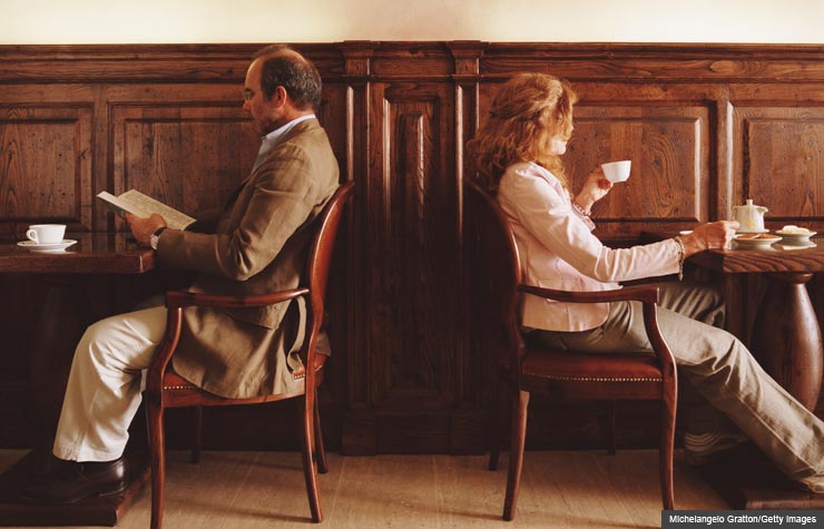 Man and woman sit back to back at a cafe.
