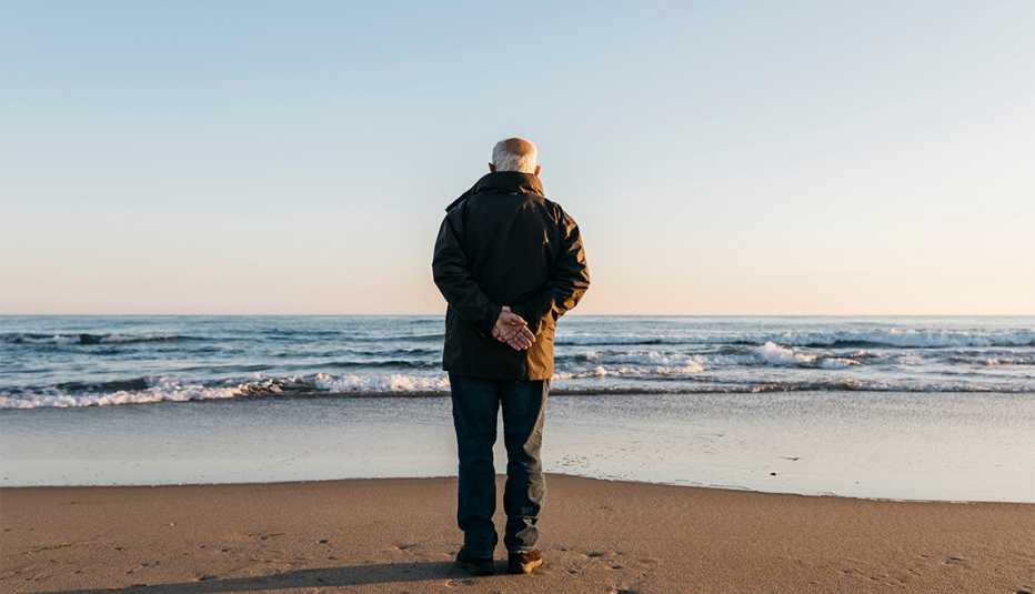 man gazing at the ocean on the beach in winter