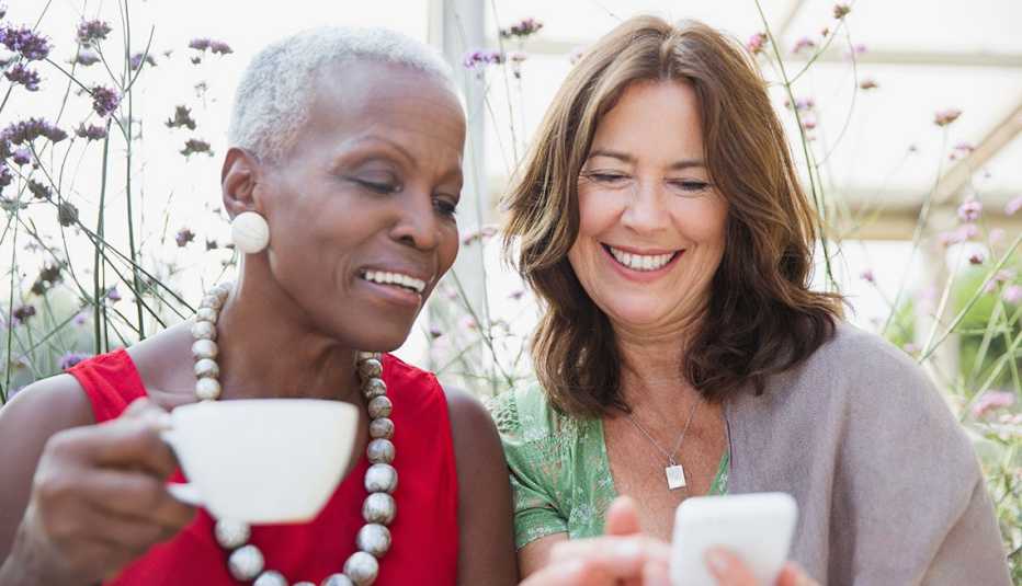 Two women looking at a mobile phone while laughing 