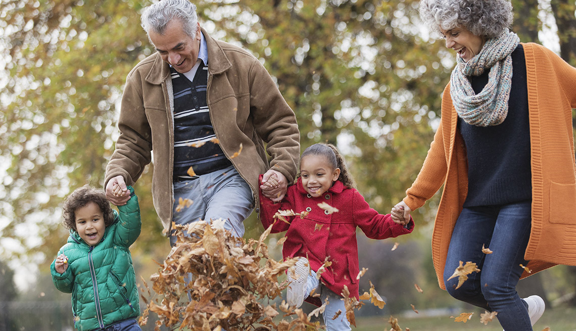 Grandparents and grandchildren walking through leaves