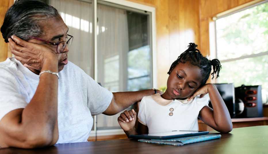 Grandmother and granddaughter at home working on a digital tablet.