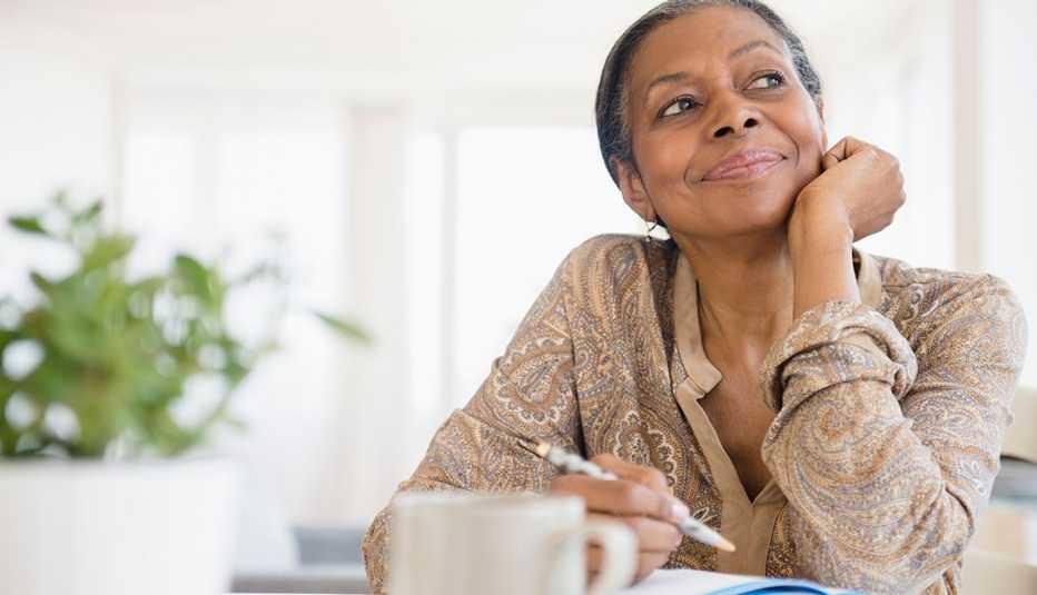 woman sitting a desk smiling while writing in a journal woman sitting a desk smiling while writing in a journal