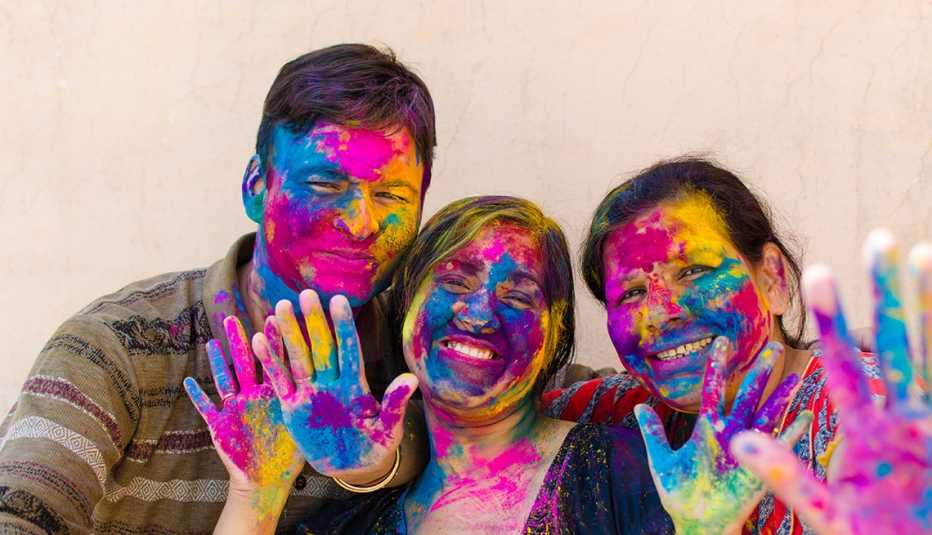 Indian family (mother son and daughter) with colorful face, smiling and looking to camera in festival Holi