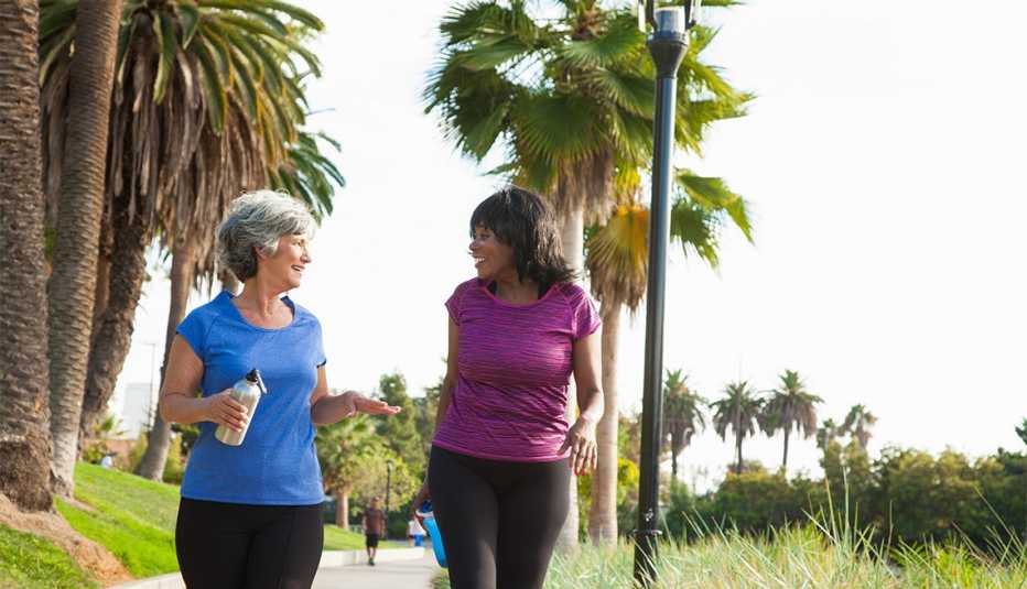 two women smiling and walking in a park
