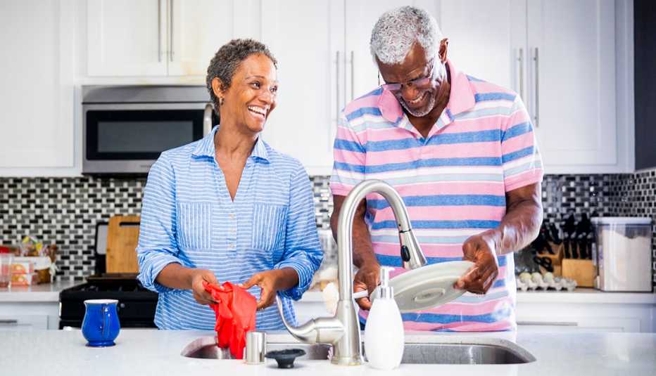 Couple in their kitchen doing the dishes together and laughing