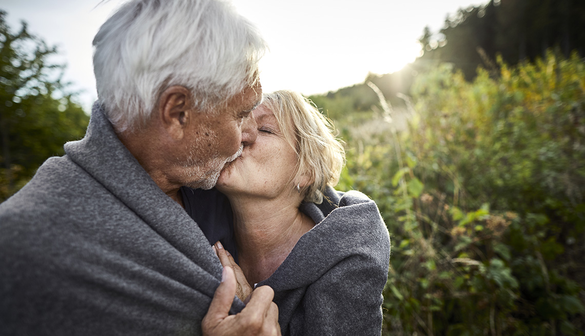Couple embracing, kissing in a field