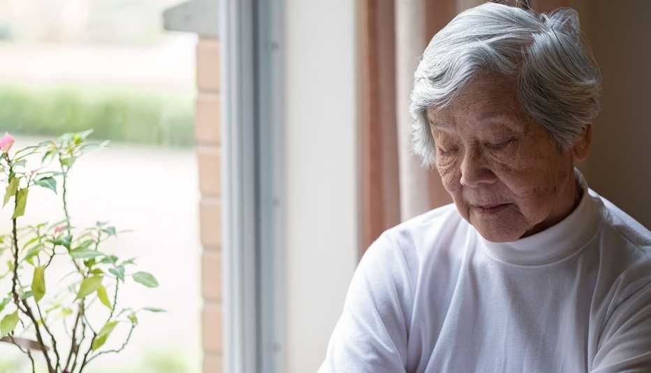 older woman sitting by window with eyes closed