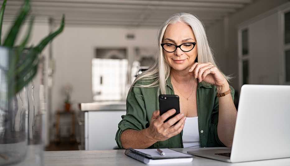 Woman making a phone call in front of a laptop.